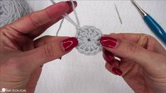 two hands are holding yarn and crochet together to make a circular ornament