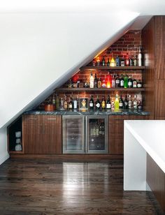 an attic bar with built in wine coolers and liquor bottles on the back wall