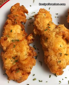 three fried chicken nuggets on a white plate with parsley sprinkles