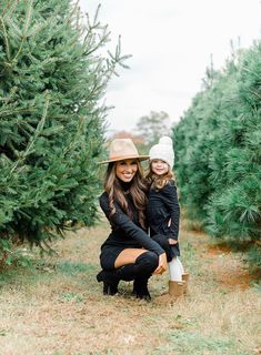 a woman and her daughter are standing in the middle of a christmas tree farm