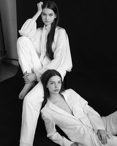 two women sitting on top of each other in white outfits, one with long hair