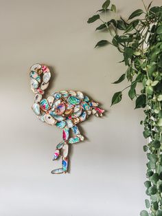 a flamingo brooch sitting on top of a wall next to a potted plant