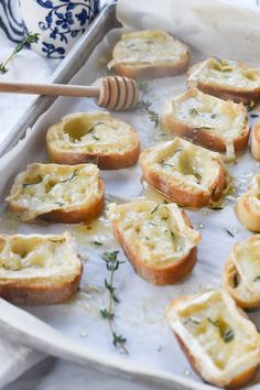 small pieces of bread with cheese and herbs in them on a baking sheet next to a honey comb