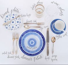 the table is set with blue and white plates, silverware, and napkins