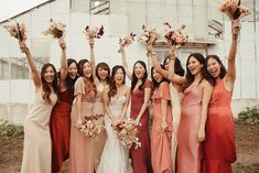 a group of women standing next to each other in front of a building holding bouquets