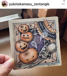 a hand holding up a piece of paper with pumpkins on it