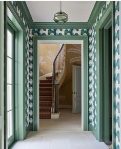 the hallway is decorated with green and white wallpaper, along with matching carpeted stairs