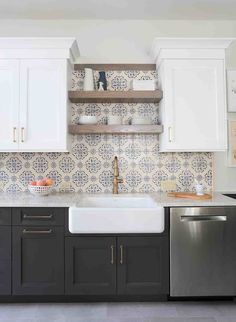 a kitchen with black and white cabinets, silver dishwasher and stainless steel sink