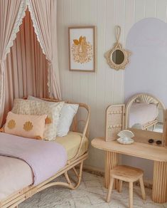 a bedroom with a bed, table and mirror in it's corner next to a window