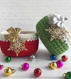 two knitted baskets decorated with christmas ornaments and bows, sitting on a white surface