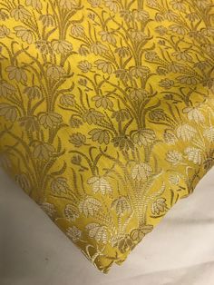 a close up of a yellow and gold fabric with flowers on the bottom half of it