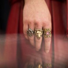 a woman's hand with three rings on it and one is wearing a red jacket