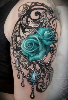 a blue rose tattoo on the back of a woman's shoulder, with an intricate design