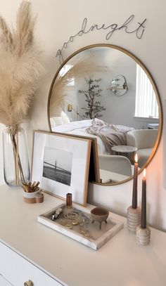 a white dresser topped with a mirror and candles