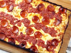 a pepperoni pizza sitting on top of a wooden cutting board