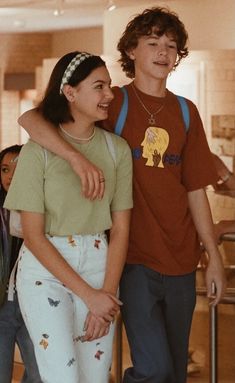 a boy and girl standing next to each other with their arms around each other in front of them