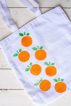 a white bag with oranges painted on it sitting on top of a wooden table