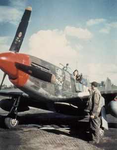 a man standing next to an airplane on top of a tarmac with another plane in the background