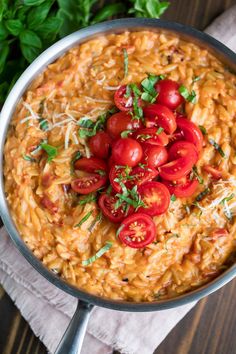 pasta with tomatoes and parmesan cheese in a skillet on a wooden table