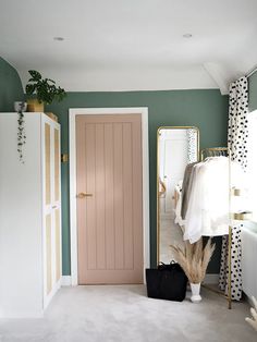 a room with green walls and white carpeting has a pink door in the corner