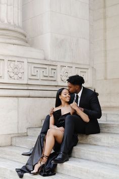 a man and woman are sitting on the steps together, one is holding her arm around the other's shoulder