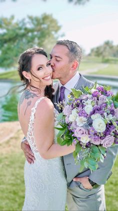 a bride and groom kissing in front of a lake