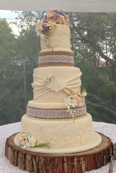 a three tiered wedding cake sitting on top of a wooden table next to a window