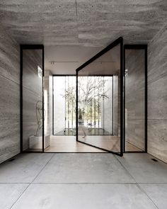 an empty room with concrete walls and glass doors