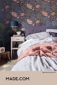 a bedroom with floral wallpaper and striped bedding