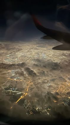 an aerial view of the city lights and clouds at night as seen from an airplane