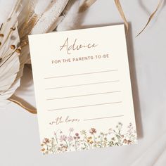 an advice card for the parents to be with flowers and feathers around it on a white surface