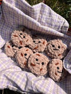 several crocheted teddy bears sitting on top of a cloth covered blanket in the grass