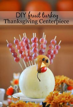 a white vase filled with grapes and a turkey head on top of a cake plate