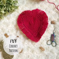 a crochet heart pattern next to scissors and other crafting supplies on a white rug