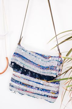 a handbag hanging on a wall next to a plant