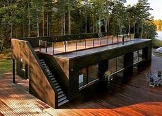 a house that is sitting on top of a wooden deck next to water and trees