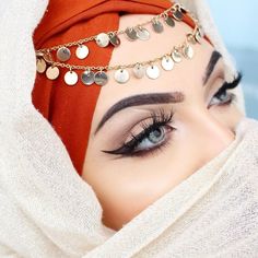 a close up of a woman wearing a hijab and eye make - up