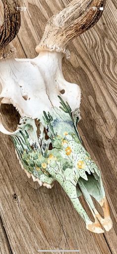 an animal skull with antlers and flowers painted on it's face sitting on a wooden floor