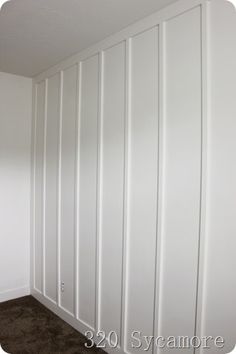 an empty room with white paneling and carpet