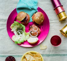 a pink plate topped with burgers and chips