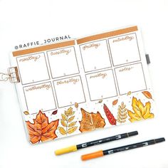 a planner with autumn leaves on it next to two markers and pencils in front of it