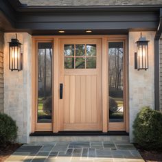 the front door to a house with two lights on each side and an entry way