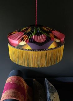 a colorful lamp hanging from a ceiling next to pillows