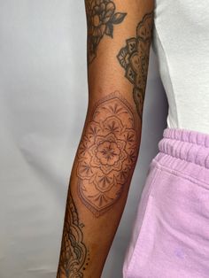 a woman's arm with tattoos on it and a flower tattoo on the wrist