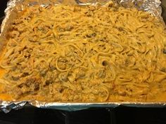 an uncooked casserole dish with noodles and meat in it on aluminum foil