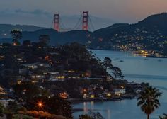 the golden gate bridge in san francisco is lit up at night with lights from nearby buildings