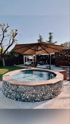 an outdoor hot tub in the middle of a yard with a large umbrella over it