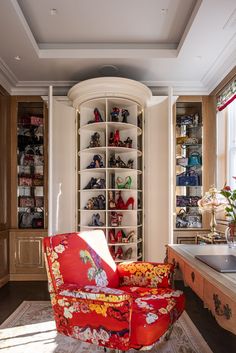 a red chair sitting in front of a white shelf filled with lots of shoe shelves