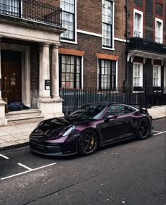 a purple sports car parked on the side of a street next to tall brick buildings