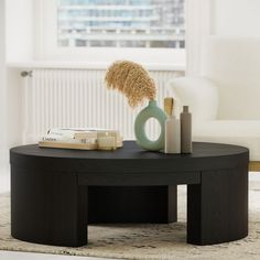 a black table with some books and a vase on it in front of a window